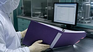 Validation technician reviewing a Validation Master Plan binder in a pharmaceutical cleanroom environment